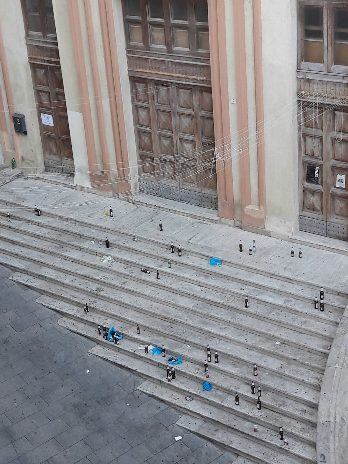 Piazza Dettori il mattino dopo: bottiglie e rifiuti lungo la scalinata