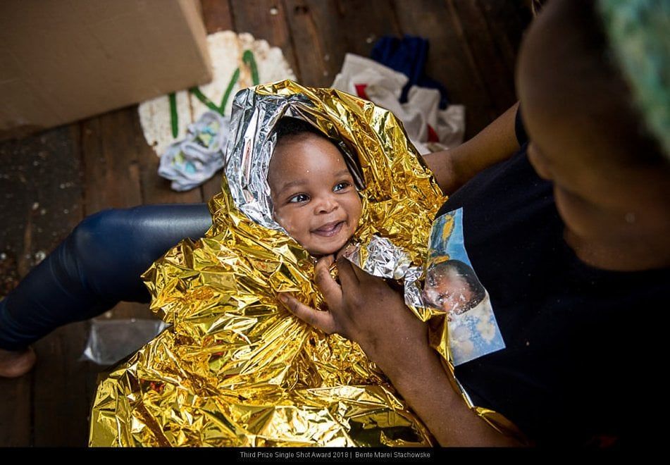 Quel sorriso che fa sperare: la foto della bimba migrante avvolta nella termocoperta è virale