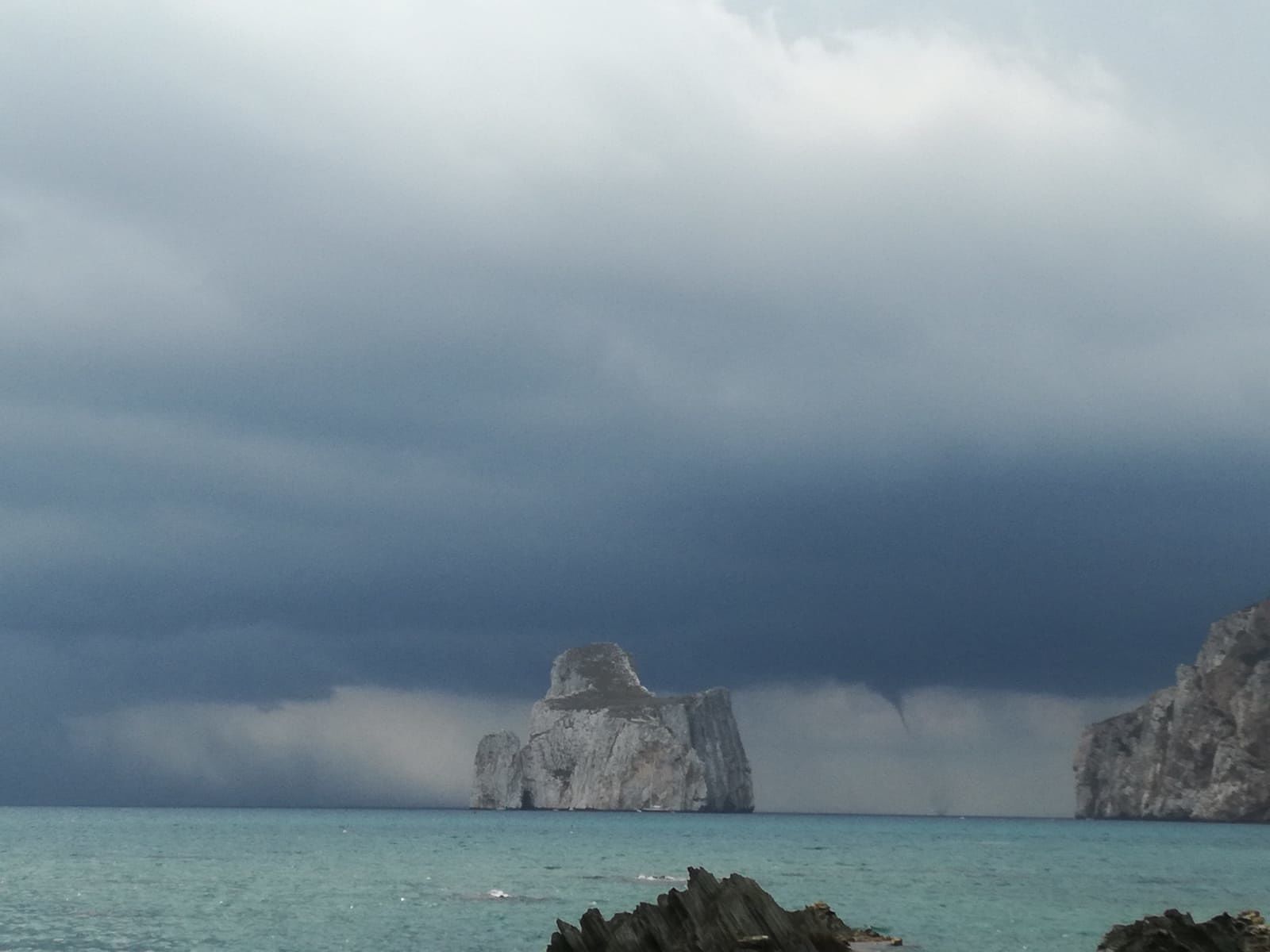 Tromba marina al Pan di Zucchero di Masua, i bagnanti in acqua guardano lo spettacolo (VIDEO)