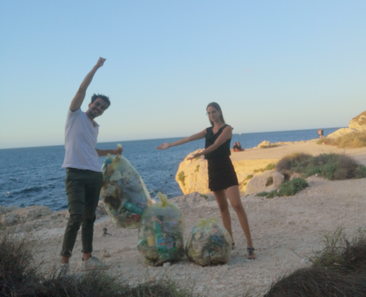 Calamosca, coppia di giovani ripulisce la spiaggia dai rifiuti: “Un gesto da esempio per tutti”