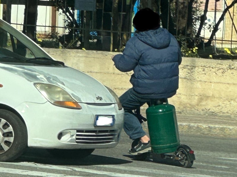 Cagliari, la guida “curiosa”: un uomo sul monopattino utilizza una bombola come sedile