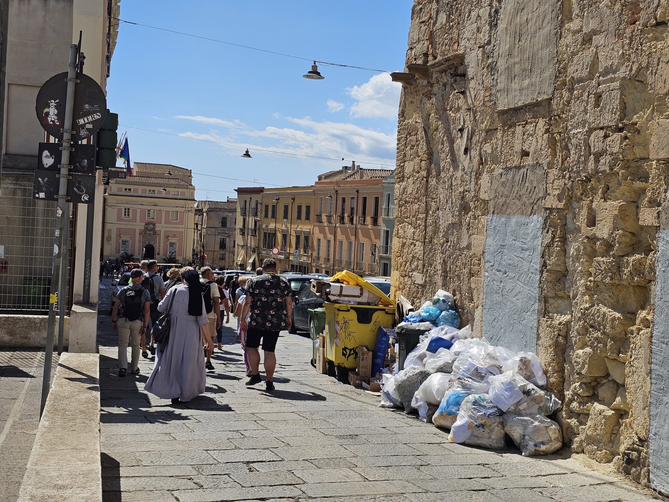 La foto choc a Cagliari, i turisti passeggiano accanto a una discarica in Castello