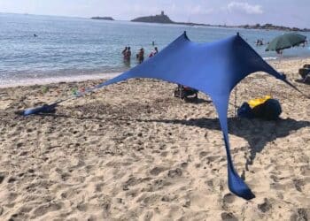 Nora, il maxi telo in spiaggia divide i bagnanti: “Sono accampamenti abusivi”. Ma c’è chi replica: “Lasciateci vivere il mare in libertà”